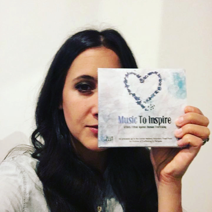A supporter holding her copy of the Music To Inspire album